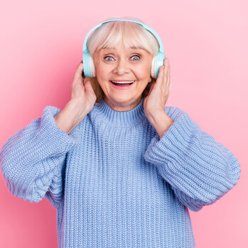 Man sieht eine Frau mit Kopfhörern vor einem rosa Hintergrund